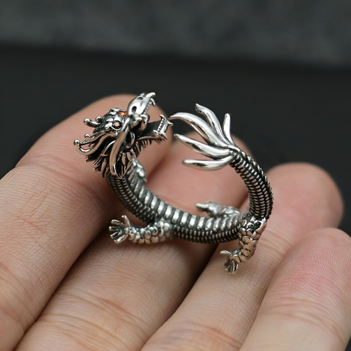 L'image montre une bague en argent en forme de dragon. Le dragon est représenté avec une tête de dragon et un corps enroulé. La bague est portée sur le doigt d'une personne.,BA-5656125335,BA-107596783X