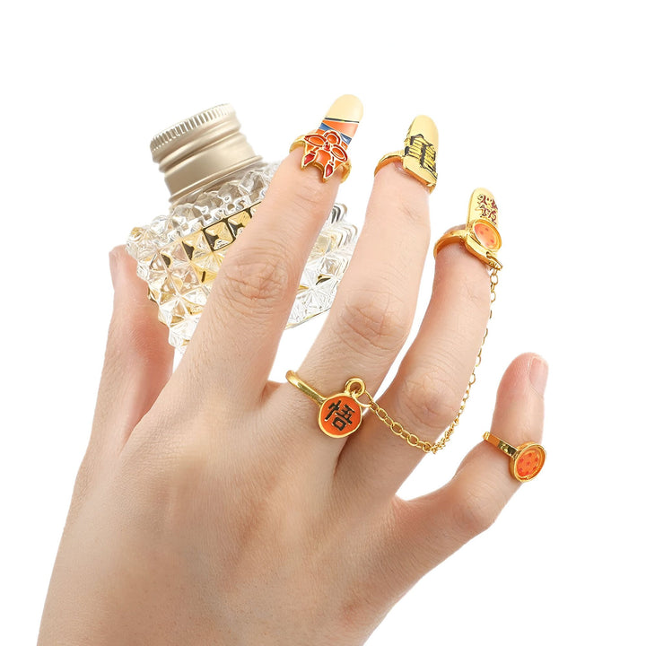 Une main porte une bague avec un pendentif en forme de capsule contenant une bille orange, une bague avec le kanji "Dieu", une bague avec un pendentif en forme de dragon, et un ongle avec un motif de Goku.,BA-1848485220