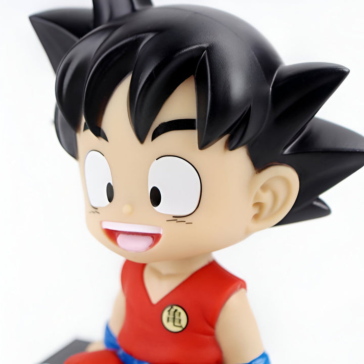 Une figurine de Son Goku, un personnage de Dragon Ball Z. Il est assis sur un socle noir et porte son costume orange et bleu. Il a les cheveux noirs et les yeux bleus.,BO-8449687543