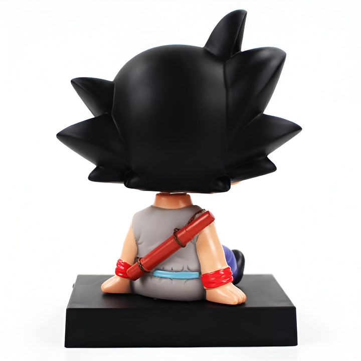 Une figurine de Son Goku, un personnage de Dragon Ball Z, assis sur un socle noir. Il est vêtu d'une combinaison orange et bleue et porte un bâton sur son dos.,BO-1118965817