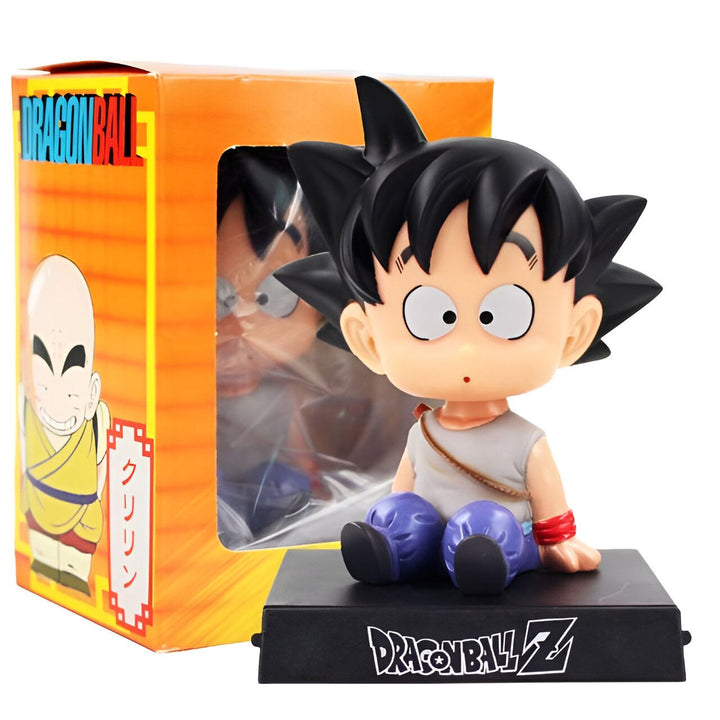 Une figurine de Son Goku, un personnage de Dragon Ball Z, assis sur un socle noir. Il porte une tenue orange et bleue et a les cheveux noirs. La figurine est dans une boîte orange et blanche.,BO-1118965817