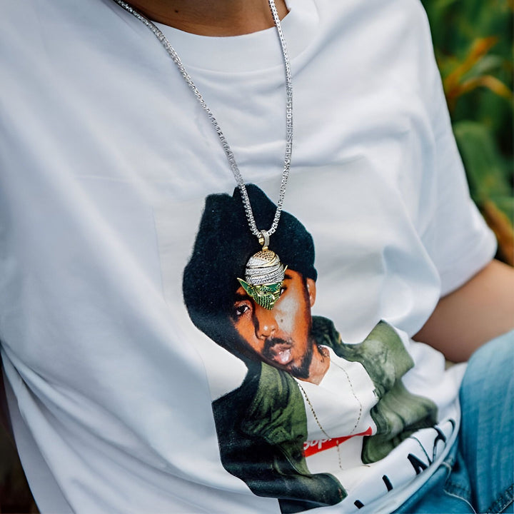 Une image d'un homme portant un t-shirt blanc avec une image de Nas, un rappeur américain, imprimée dessus. L'homme porte également une chaîne en or avec un pendentif en forme de personnage de dessin animé.,CO-5123169970,CO-294831724X