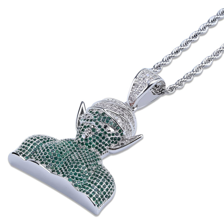 Un pendentif en forme de tête de Piccolo, un personnage de Dragon Ball Z, avec des pierres précieuses vertes et blanches.