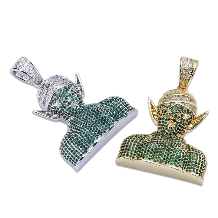 Deux pendentifs en forme de tête de Piccolo, un personnage de Dragon Ball Z. Le pendentif de gauche est en argent et celui de droite est en or. Les deux pendentifs sont sertis de pierres précieuses vertes.