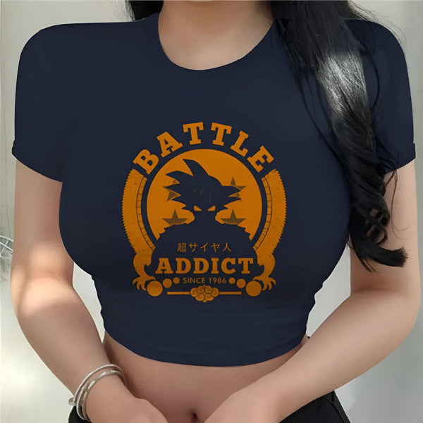 Une jeune femme porte un crop top noir avec un imprimé orange. Le texte imprimé est "Battle" et "addict" avec un personnage de dessin animé.,CR-7495104961,CR-7179193623,CR-5720647503,CR-4824996805,CR-8457156543,CR-6189858449,CR-6955880454