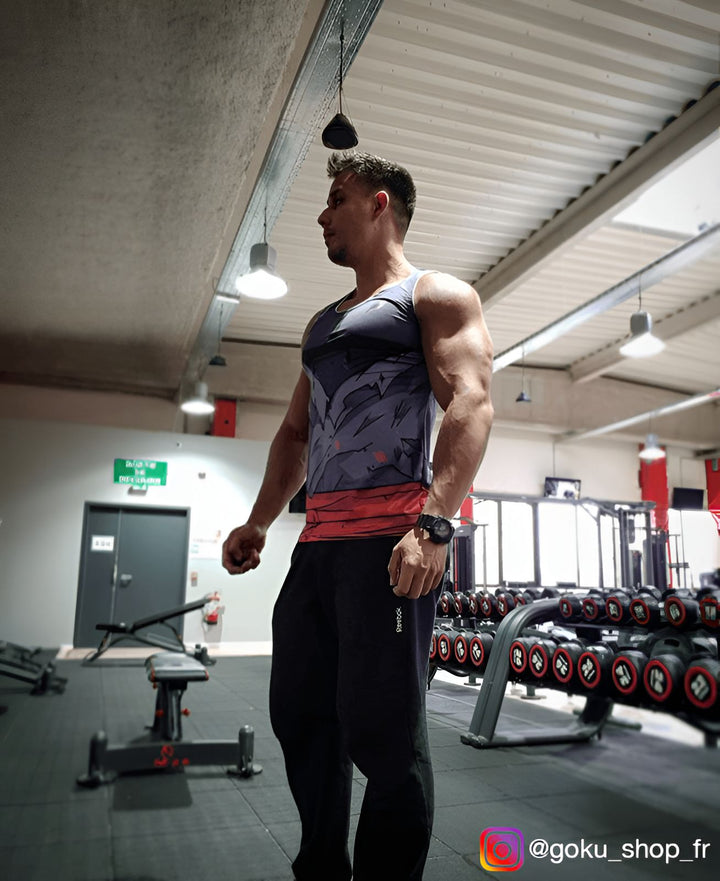 Un homme portant un débardeur Dragon Ball Z et un pantalon de survêtement noir est debout dans une salle de sport. Il regarde vers la droite.,DS-4047599255,DS-2512076253,DS-4881455028,DS-0946741298,DS-2293702103,DS-0741294826