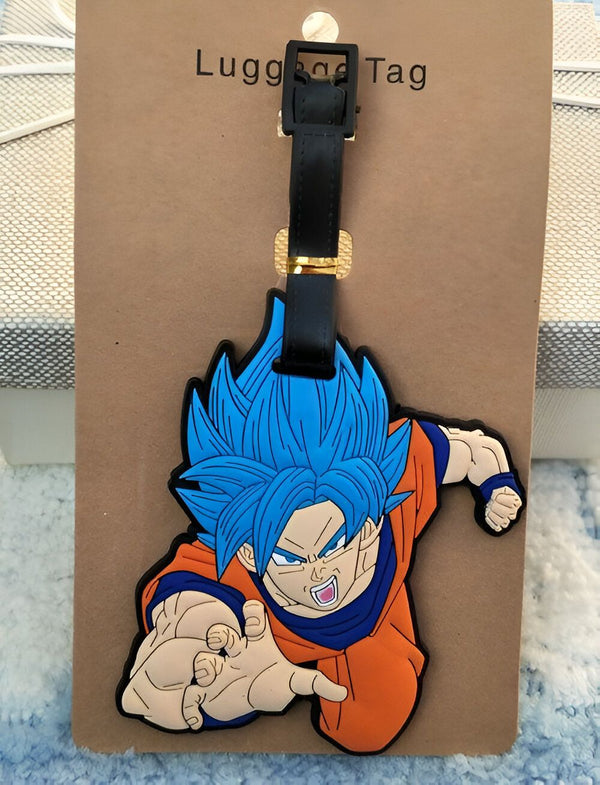 Un porte-étiquette de bagage en caoutchouc à l'effigie de Son Goku, un personnage de la série animée Dragon Ball Z. Son Goku est représenté en train de voler, avec ses cheveux bleus et sa combinaison orange. Le porte-étiquette est de couleur marron et possède une attache en cuir noir.,É-1075265088