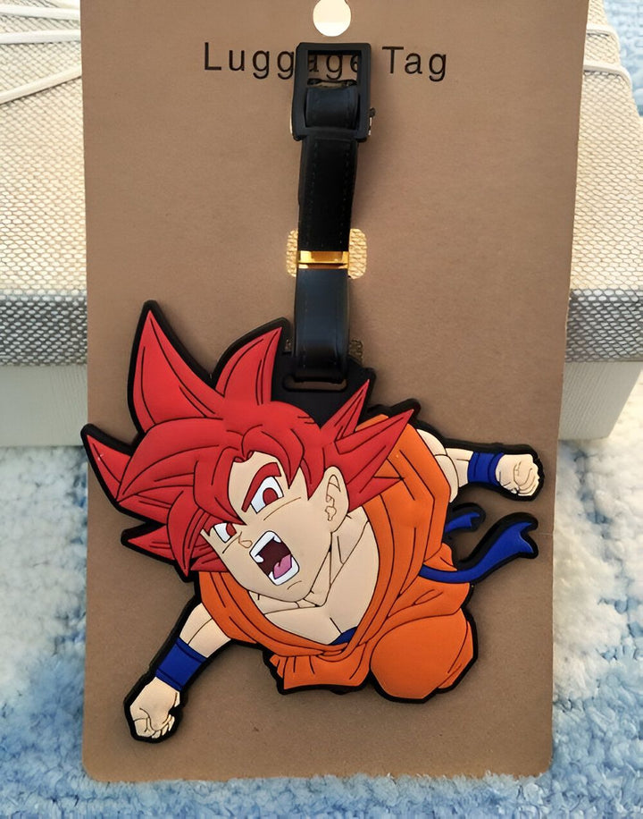 Un porte-étiquette de bagage en caoutchouc à l'effigie de Son Goku, un personnage de la série animée Dragon Ball Z. Il est représenté en train de se battre, avec ses cheveux rouges hérissés et sa combinaison orange.,É-8600482720