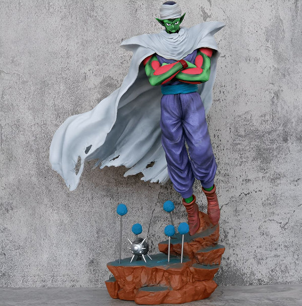 Une figurine de Piccolo, un personnage de Dragon Ball Z. Il est vêtu d'un pantalon violet et d'une cape blanche. Il a les cheveux verts et les yeux jaunes. Il est en train de se battre contre un adversaire.,FI-3293092977