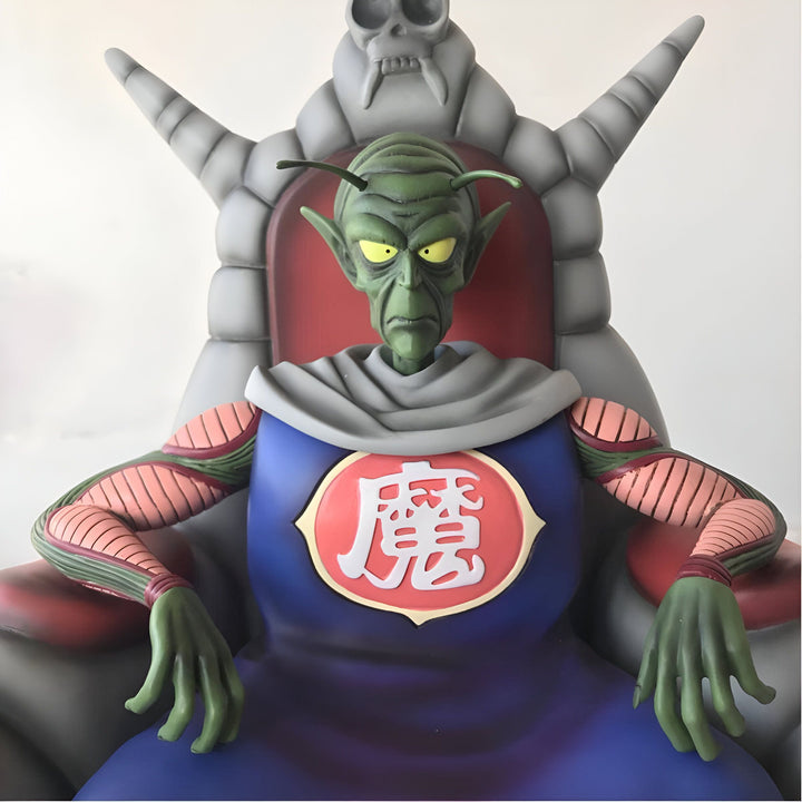Une image de Piccolo, un personnage de Dragon Ball Z, assis sur un trône. Il porte une longue cape bleue et une couronne. Il a la peau verte et des cheveux blancs. Il est assis sur un trône de pierre avec un crâne sur le dossier.,FI-3475373424