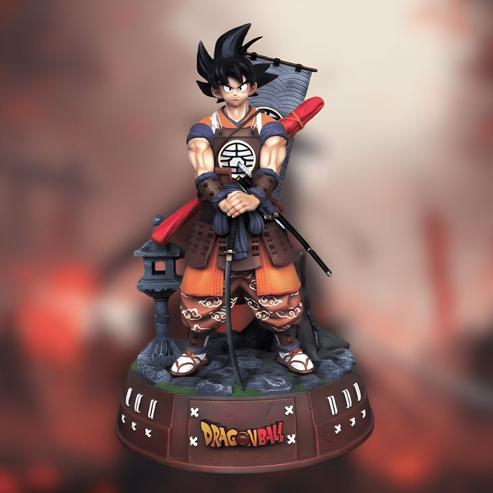 Une figurine de Son Goku, un personnage de Dragon Ball Z, vêtu d'une armure de samouraï. Il tient un katana dans sa main droite et un fourreau dans sa main gauche. La figurine est posée sur un socle rond noir et rouge avec le logo Dragon Ball Z.,FI-1944569502
