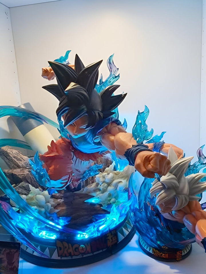 Une image de deux figurines de Dragon Ball Z, Goku et Vegeta, en train de se battre. Goku est en train de donner un coup de poing à Vegeta. Vegeta est en train de se défendre avec son bras. Les deux personnages sont entourés d'un aura bleue. La figurine de Goku est éclairée par une lumière bleue.,FI-5169885547