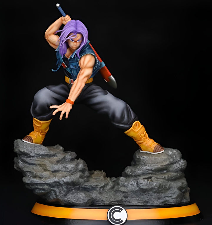 Une figurine de Trunks du futur, un personnage de Dragon Ball Z. Il est vêtu d'une veste bleue et d'un pantalon noir. Il a les cheveux violets et les yeux bleus. Il est en position de combat, tenant une épée dans sa main droite. Il se tient sur un rocher.,FI-7389337834