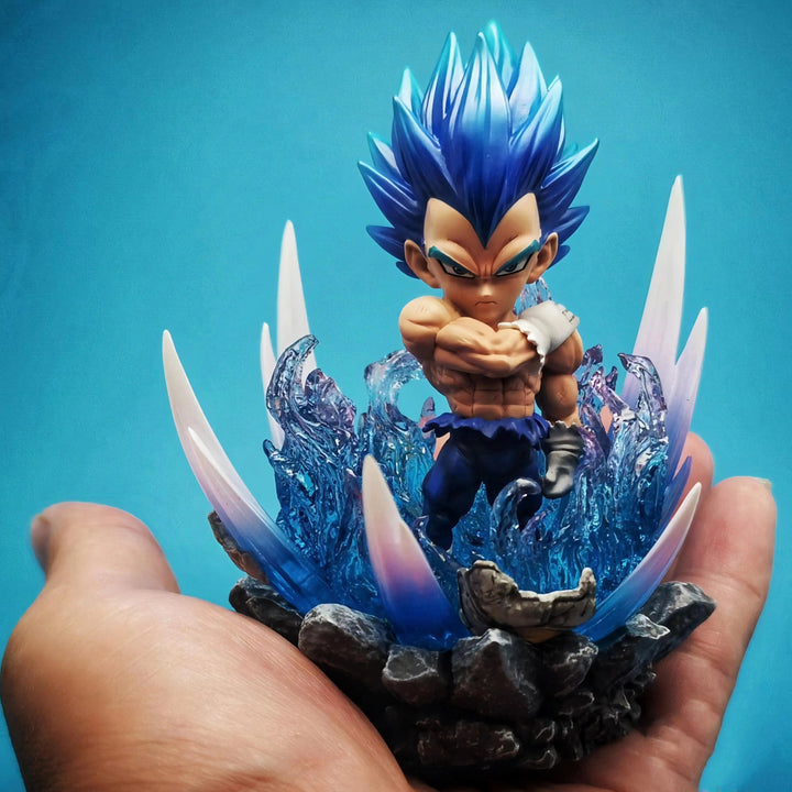 Une figurine de Vegeta, un personnage de Dragon Ball Z, est posée sur la paume d'une main. Vegeta est un Saiyan, une race extraterrestre connue pour sa force et ses pouvoirs de combat. Il est le prince des Saiyans et le rival de Goku, le protagoniste de la série. La figurine est en résine et mesure environ 10 cm de haut. Elle est très détaillée et représente Vegeta dans sa tenue de combat bleue. La figurine est posée sur un socle en plastique transparent qui lui permet de tenir debout.,FI-632171478X