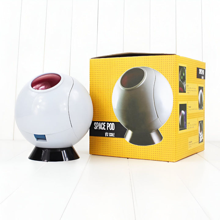 Une image d'une figurine de la capsule spatiale de Dragon Ball Z. La capsule est blanche et rouge avec un dôme transparent. Elle est posée sur un socle noir. A côté se trouve la boite de la figurine.,FI-4521685544