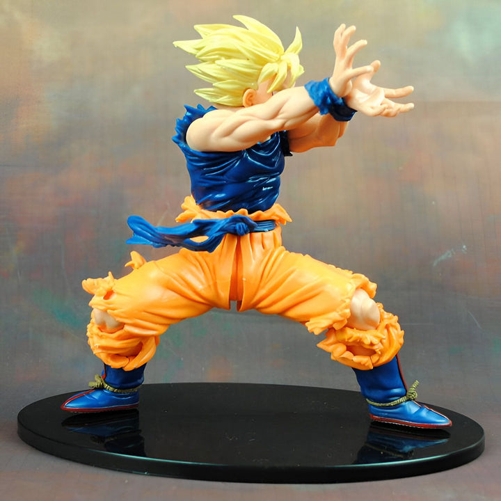 Une figurine de Son Goku, un personnage de la série animée Dragon Ball Z. Il est représenté en position de combat, avec les cheveux jaunes hérissés, le regard déterminé et les poings serrés. Il porte une combinaison orange et bleue déchirée, et des bottes orange et bleues. La figurine est posée sur un socle noir.,FI-8241401833