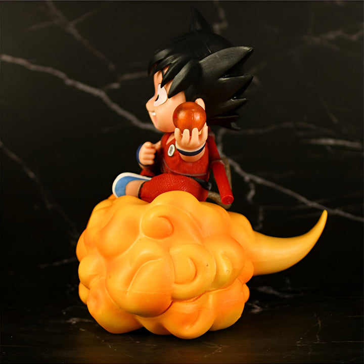 Une figurine de Son Goku, un personnage de Dragon Ball Z, assis sur un nuage magique orange. Il porte une combinaison orange et tient une boule de cristal dans sa main droite.,FI-9809827229