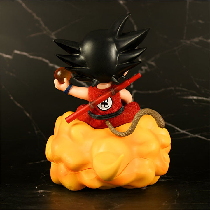 Une figurine de Son Goku, un personnage de Dragon Ball Z, assis sur un nuage magique. Il porte une combinaison orange et une ceinture bleue. Il a les cheveux noirs et les yeux bleus. Il tient une boule de cristal dans sa main droite.,FI-9809827229