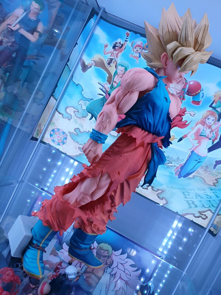 Une figurine de Son Goku, un personnage de la série animée Dragon Ball Z. Il est représenté avec ses cheveux blonds hérissés, sa combinaison orange déchirée et ses bottes bleues. Il se tient debout sur un socle blanc et est entouré d'autres figurines de la série.,FI-4930058376
