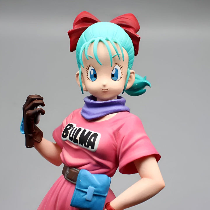 Une figurine de Bulma, un personnage de Dragon Ball Z. Elle porte une combinaison rose et une ceinture marron. Elle a les cheveux bleus et les yeux bleus. Elle est souriante et tient un téléphone portable à la main.,FI-1374037761