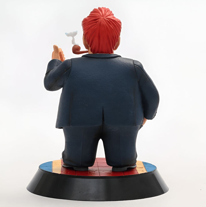 Une figurine de Donald Trump est représentée de dos. Il porte un costume bleu et une cravate rouge. Il fume la pipe et a les cheveux roux. Il est debout sur un socle rond rouge, bleu et jaune.,FI-506968812X
