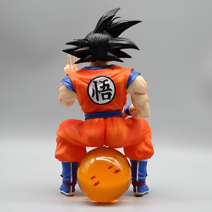 Une figurine de Son Goku assis sur une boule de cristal. Il est vêtu de son costume orange et bleu et a les cheveux noirs. Il est en train de faire un signe de la main.,FI-7303422293