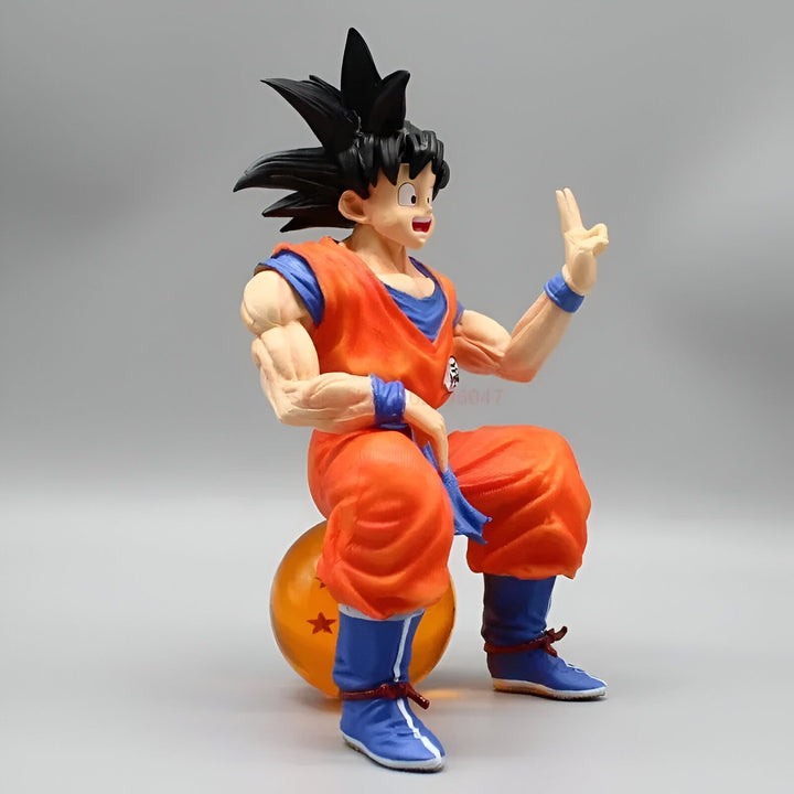 Une figurine de Son Goku, un personnage de la série animée Dragon Ball Z. Il est assis sur une boule de cristal et porte son costume orange et bleu. Il sourit et fait un signe de la main.,FI-7303422293