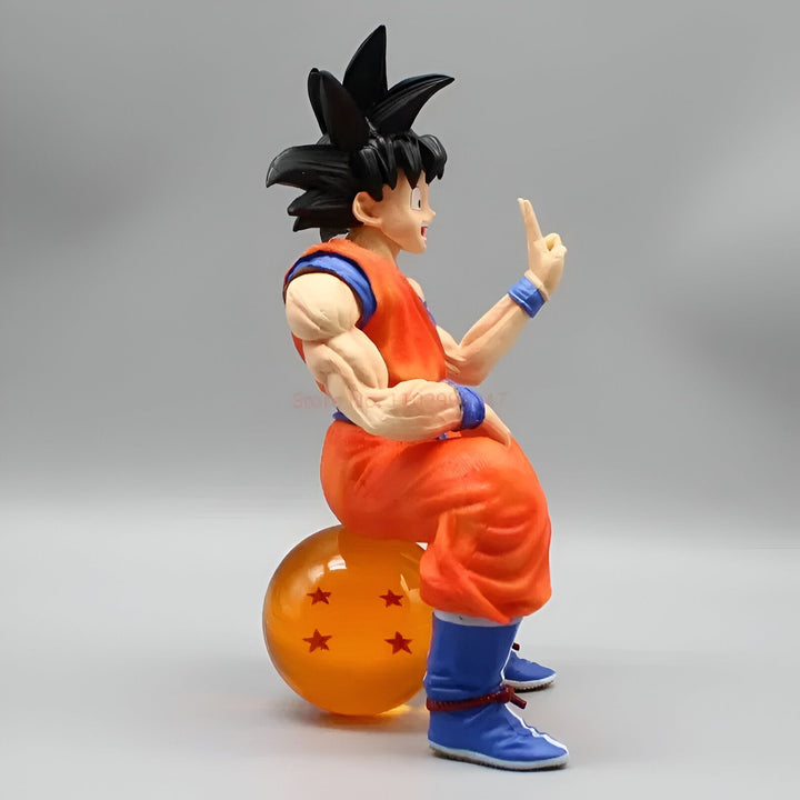 Une figurine de Son Goku assis sur une boule de cristal à quatre étoiles. Il porte son costume orange et bleu et a un doigt levé.,FI-7303422293