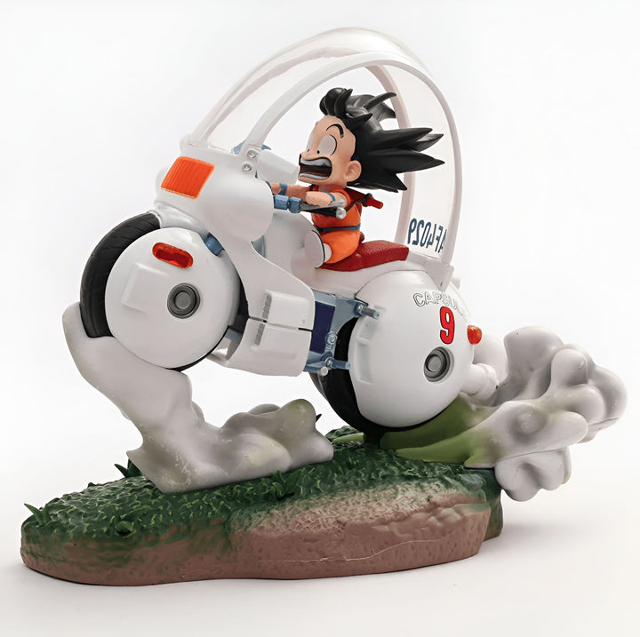 Une figurine de Son Goku chevauchant sa moto volante. Il est vêtu de sa combinaison orange et de son casque. La moto est blanche et possède un numéro 9 sur le côté. Elle est également équipée d'un guidon et d'un siège. Son Goku a les cheveux noirs et les yeux bleus. Il est souriant et semble heureux de conduire sa moto. La figurine est posée sur un socle vert.,FI-2535602881