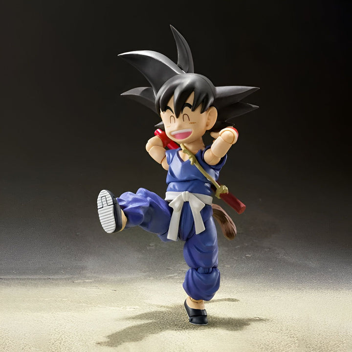 Une figurine de Son Goku, un personnage de Dragon Ball Z. Il est vêtu d'un kimono bleu et d'une ceinture orange. Il a les cheveux noirs et les yeux bleus. Il est en train de sourire et de se tenir sur une jambe.,FI-3055026829