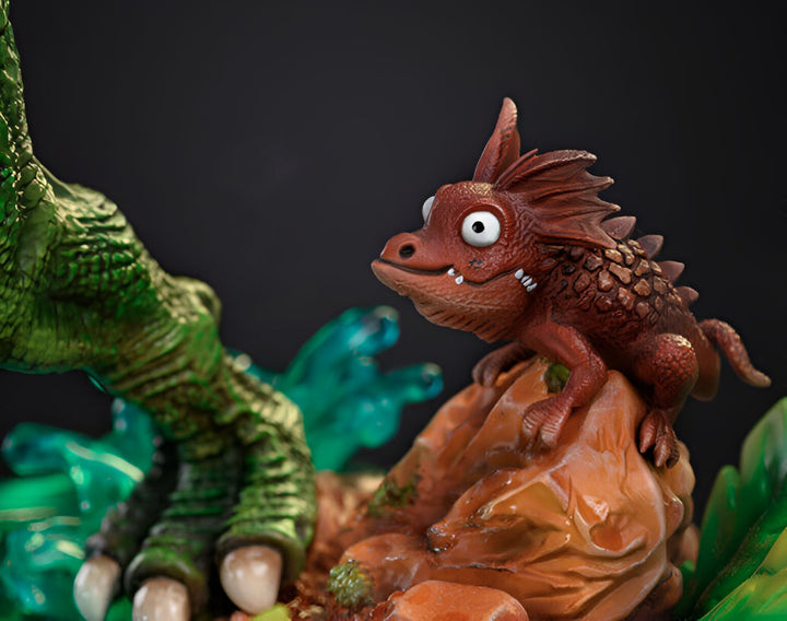 Une figurine en résine d'un petit lézard brun avec des yeux globuleux et une bouche souriante. Il est perché sur un rocher et regarde un grand dinosaure vert.,FI-3980047431