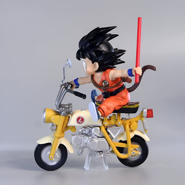Une figurine de Son Goku, un personnage de Dragon Ball, sur une moto jaune. Il porte une combinaison orange et des chaussures bleues. Il a les cheveux noirs et les yeux bleus. La moto a un siège marron et un guidon noir.,FI-9738210933