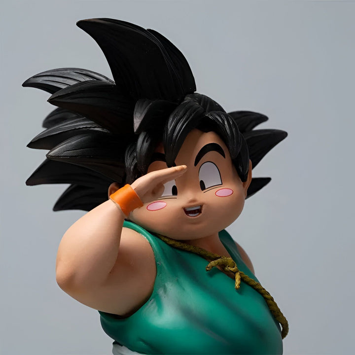 Une figurine en plastique de Son Goku enfant, un personnage de la série animée Dragon Ball Z. Il est représenté avec ses cheveux noirs hérissés, son visage souriant et sa main droite levée en l'air. Il porte une combinaison verte et orange.,FI-0030491541