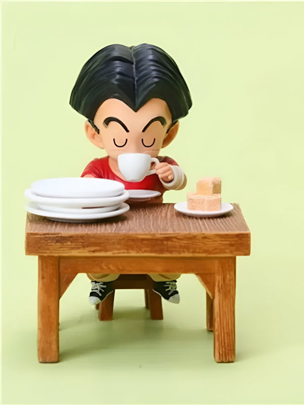 Une figurine de Krilin assis à une table et buvant une tasse de thé. Il y a une assiette de biscuits sur la table.,FI-8675403569