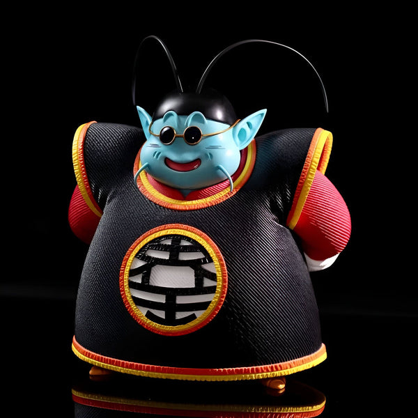 Une figurine de collection de King Kai, un personnage de la série animée Dragon Ball Z. Il est représenté avec sa tenue traditionnelle, un pantalon rouge et une veste noire avec le symbole de la planète Terre. Il a également ses lunettes de soleil et un sourire sur le visage. La figurine est fabriquée en PVC et mesure environ 15 cm de haut.,FI-1264161948