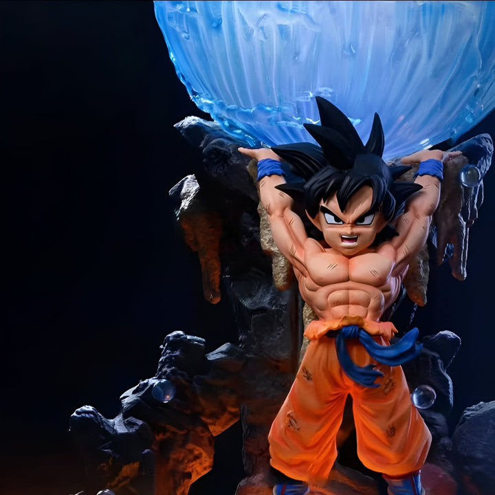 Une figurine de Son Goku, un personnage de Dragon Ball Z, en train de soulever une boule d'énergie. Il est vêtu de son costume orange et bleu et a les cheveux noirs. La figurine est posée sur un socle rocheux.,FI-6432615402