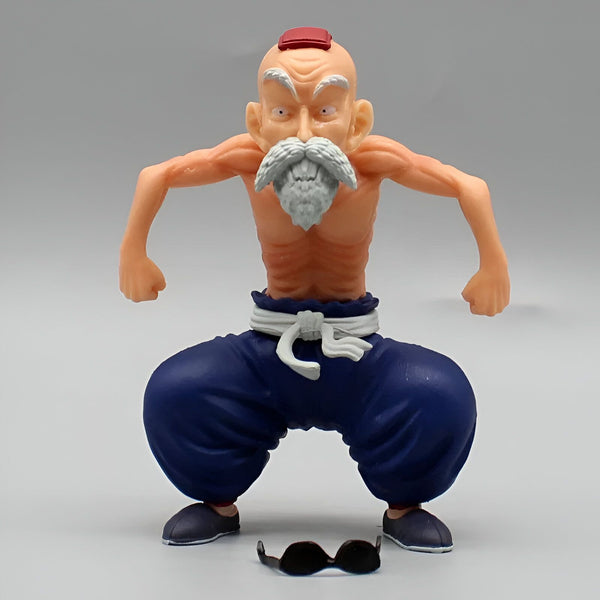 Une figurine de Muten Roshi, un personnage de Dragon Ball. Il est représenté avec sa tenue d'entraînement, un pantalon bleu et une ceinture blanche. Il a les cheveux blancs et une longue barbe. Il est en position de combat, avec les poings serrés et les jambes écartées. Il y a des lunettes de soleil à ses pieds.,FI-1396618392