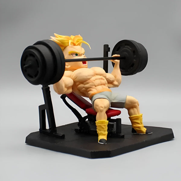 Une figurine de Trunks, un personnage de Dragon Ball Z, en train de soulever des poids. Il est assis sur un banc et porte un short gris et des chaussures jaunes. La figurine est détaillée et montre les muscles de Trunks.,FI-9270442446