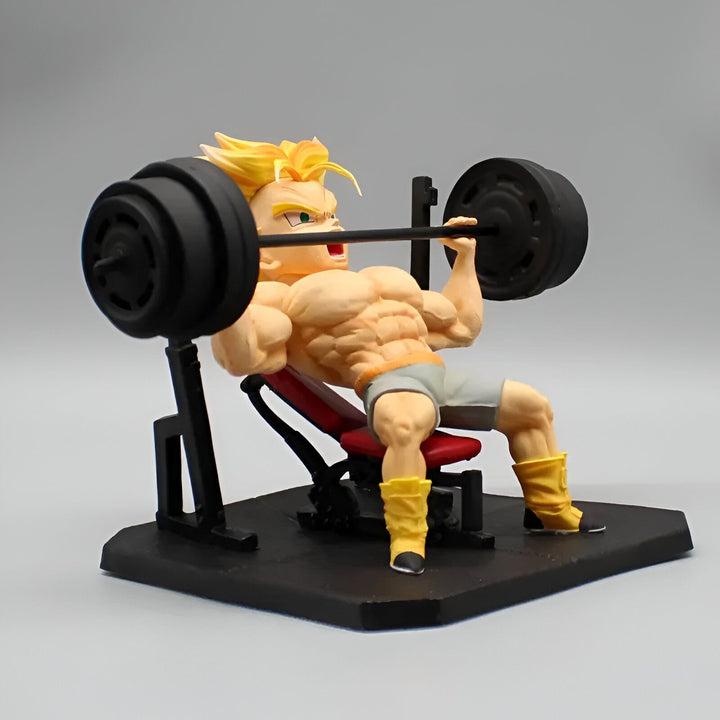 Une figurine de Trunks, un personnage de Dragon Ball Z, en train de soulever des poids. Il est assis sur un banc et porte un short gris et des chaussures jaunes. La figurine est détaillée et montre les muscles de Trunks.,FI-9270442446