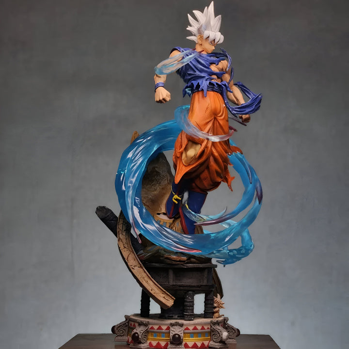 Une figurine de Son Goku, un personnage de la série animée Dragon Ball Z. Il est représenté en train de voler, avec les cheveux blancs et le corps entouré d'une aura bleue. Il porte un gi orange et des bottes bleues. La figurine est posée sur un socle marron et mesure environ 30 cm de haut.,FI-544095855X