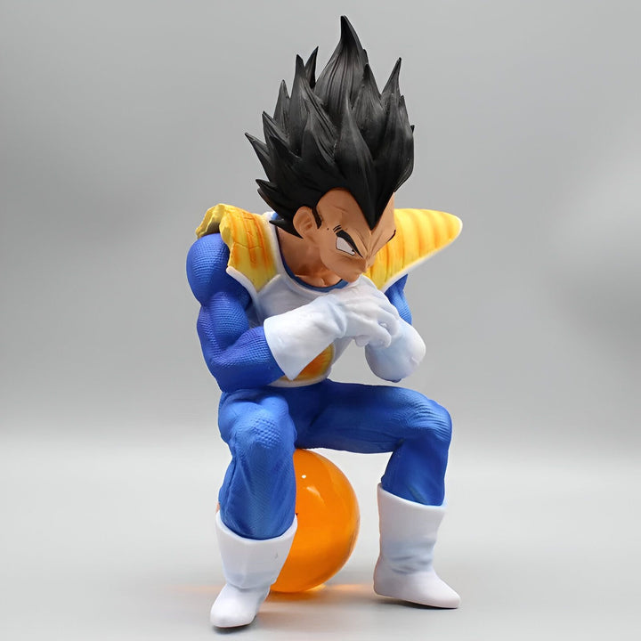 Une figurine de Vegeta, un personnage de Dragon Ball Z, assis sur une boule orange. Il porte une combinaison bleue et jaune et a les cheveux noirs.,FI-0289673437