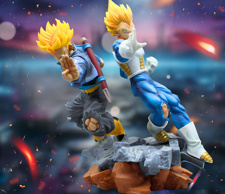 Une image de deux figurines de Dragon Ball Z, Trunks et Vegeta, en position de combat. Trunks est sur la gauche, vêtu d'une veste bleue et d'un pantalon noir. Il a les cheveux jaunes et les yeux bleus. Il tient une épée dans sa main droite. Vegeta est sur la droite, vêtu d'une combinaison bleue et jaune. Il a les cheveux jaunes et les yeux bleus. Il a les poings levés, prêts à attaquer.,FI-889710455X