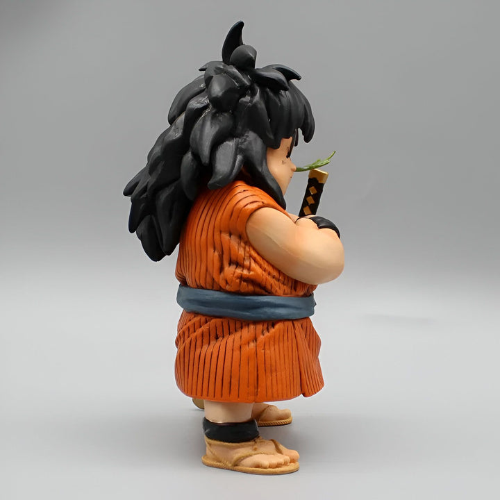 Une figurine de Yajirobé, un personnage de Dragon Ball, est représentée de profil. Il porte une tenue orange et bleue et a les cheveux longs et noirs. Il tient une épée dans sa main droite et a un brin d'herbe dans la bouche.,FI-546999421X