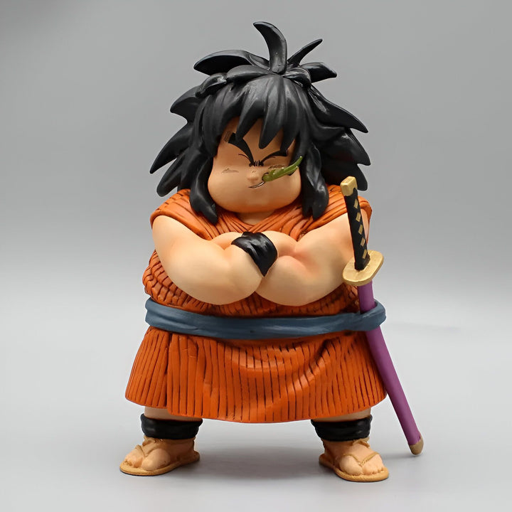 Une figurine en plastique du personnage Yajirobé de la série Dragon Ball Z. Il est représenté avec un air arrogant, les bras croisés sur son ventre, et porte une épée violette à la hanche. Il a les cheveux noirs et porte une tenue orange et bleue.,FI-546999421X