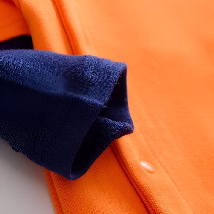 Une manche de couleur bleu marine d'un vêtement pour bébé avec des boutons-pression oranges.,GR-7171608786,GR-1168178649,GR-5392673953,GR-9178063523,GR-3933005612,GR-9569868449,GR-5166007050,GR-6557248405,GR-9720434694,GR-8916103274