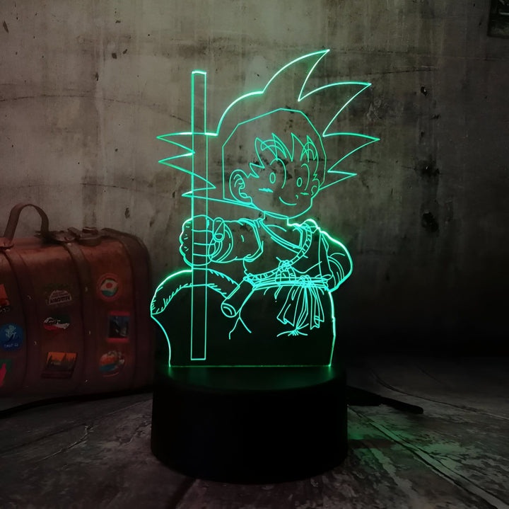 Une image d'un jeune garçon, Son Goku, assis sur un rocher, tenant un bâton à la main. Il est vêtu d'une combinaison orange et d'un gilet bleu. La lumière verte de la lampe le fait ressortir de l'arrière-plan sombre.,LA-5657397061
