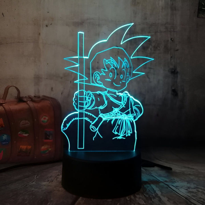L'image représente une veilleuse 3D de Son Goku, un personnage de la série animée Dragon Ball Z. La veilleuse est éclairée par une lumière LED bleue et diffuse une lumière douce et agréable. Elle est fabriquée en plastique et mesure environ 15 cm de haut.,LA-5657397061
