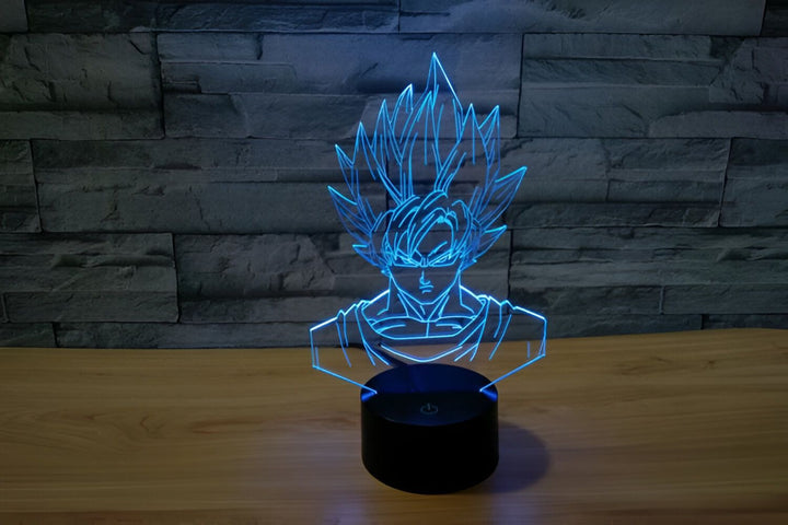 Une lampe en acrylique représentant Son Goku, un personnage de la série animée Dragon Ball Z. La lampe est éclairée par une lumière LED bleue et repose sur un socle noir.,LA-2426691638