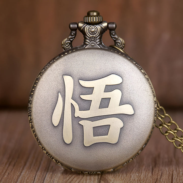 Une image d'une montre de poche en métal avec un cadran doré et une chaîne. Le cadran est orné d'un symbole chinois signifiant "force".,MO-0749564164