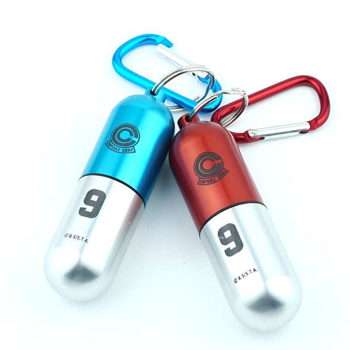 Deux porte-clés en forme de capsule contenant des pilules. La capsule bleue est numérotée 9 et la capsule rouge est numérotée 9.,PO-8470058347,PO-3235682589